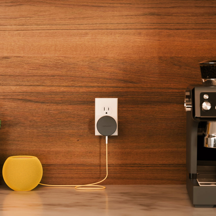Smart plug with a yellow lamp and coffee machine on a wooden surface