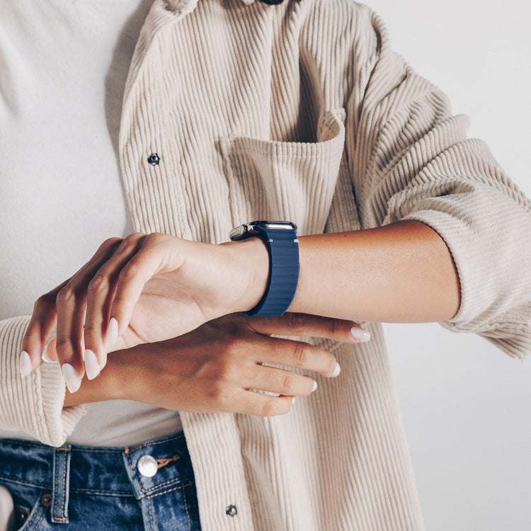 Person wearing a blue smartwatch on a plain background