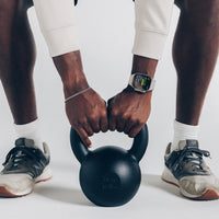 Two people holding a black kettlebell together on a white background