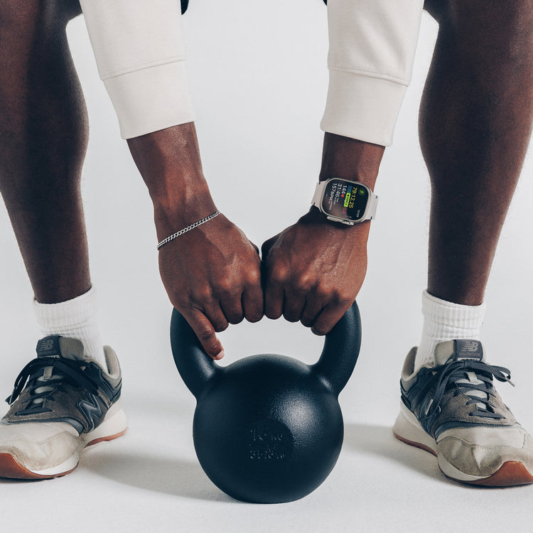 Two people holding a black kettlebell together on a white background